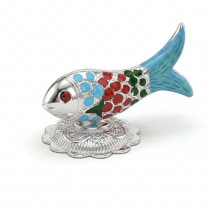 A colorful pure silver fish figurine decorated with red, blue, and green enamel, resting on a carved silver base plate over a white surface.