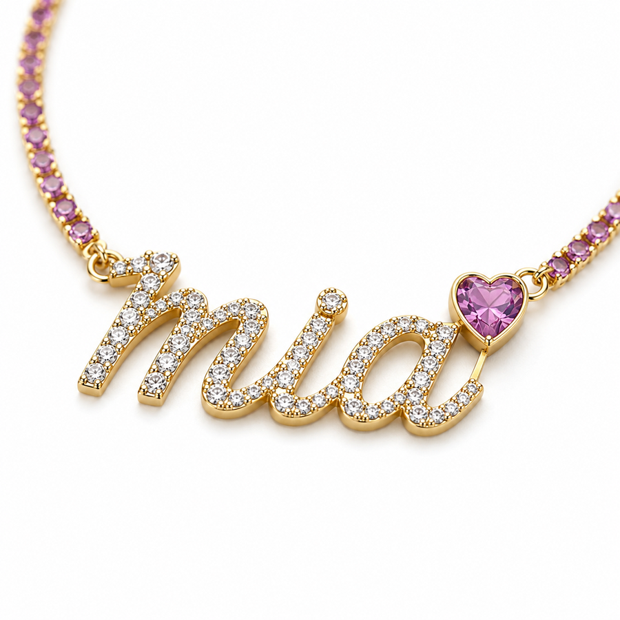 A gold-toned 925 sterling silver pet necklace displaying a stone-encrusted custom script charm spelling 'Mia' next to a pink heart gemstone.