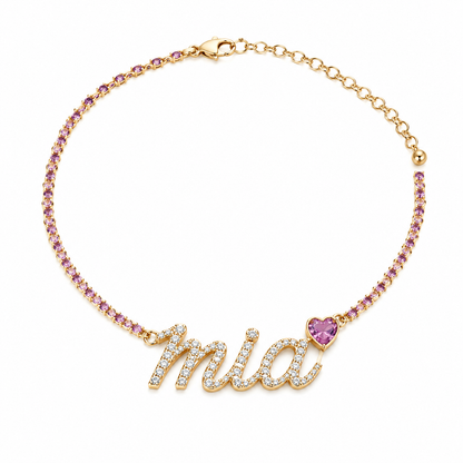 A gold-toned 925 sterling silver pet necklace displaying a stone-encrusted custom script charm spelling 'Mia' next to a pink heart gemstone necklace