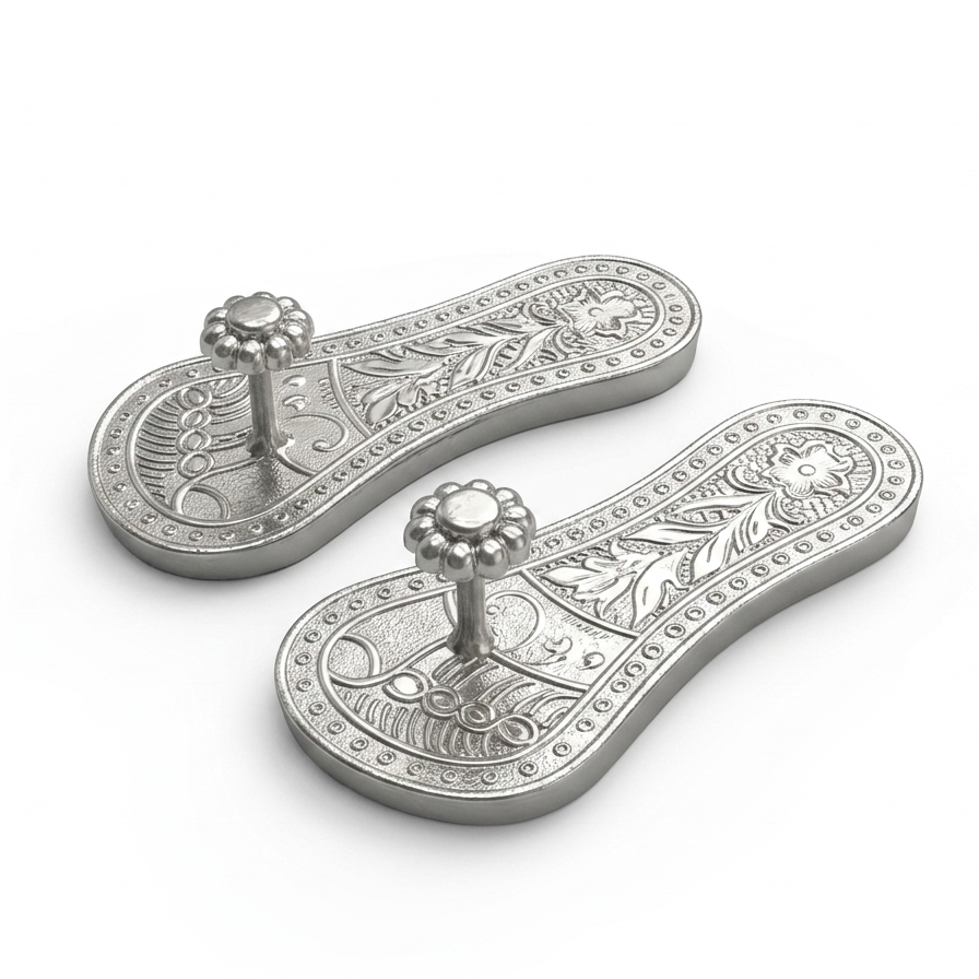 A pair of pure silver raised traditional Khadau footwear featuring detailed floral patterns, shown against a plain light background.