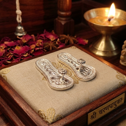 Decorative silver sandals on a fabric-covered wooden platform with a lit candle and bell in the background.