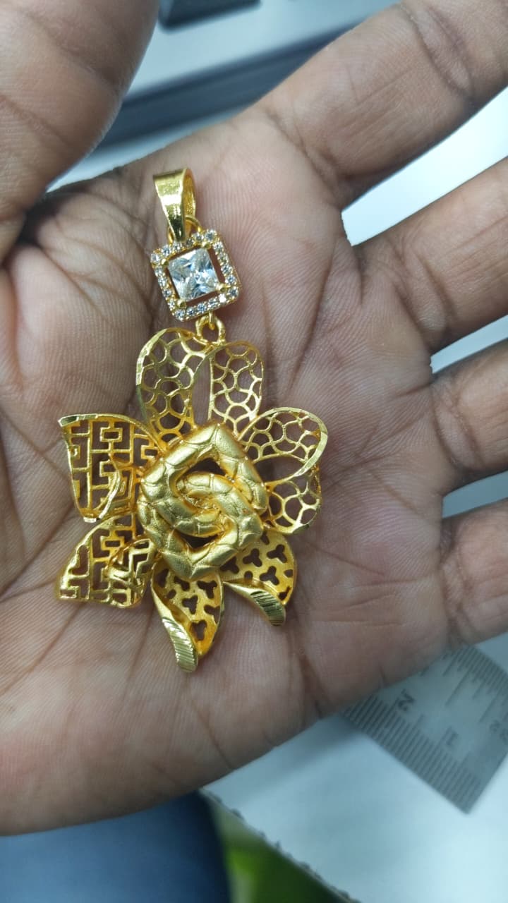 Floral Statement Pendant in gold-plated sterling silver, showcasing an intricate openwork multi-layered geometric petal pattern with a square crystal bezel bail held in hand by Rivansh.
