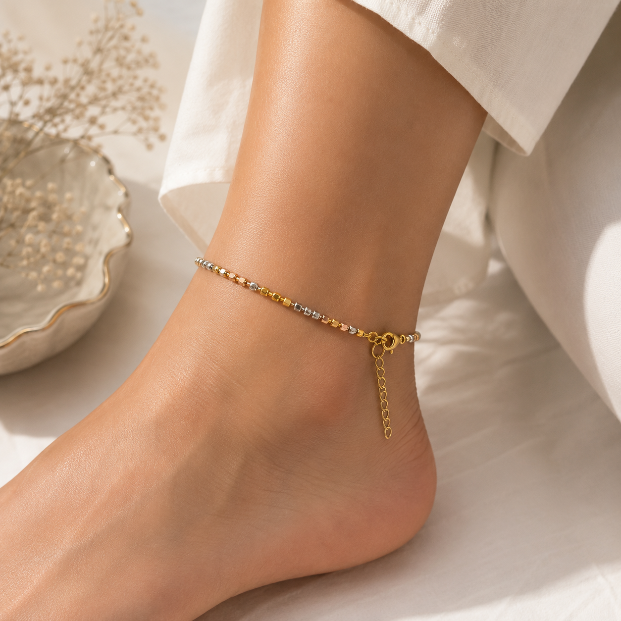 Gold anklet on a foot with a white background