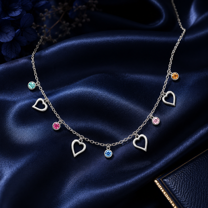 Necklace with heart-shaped pendants and colorful stones on a dark blue satin background