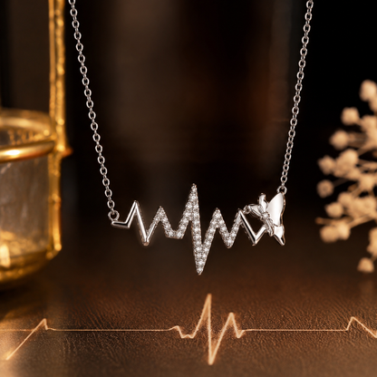 Necklace with heart rate and butterfly design on a dark surface