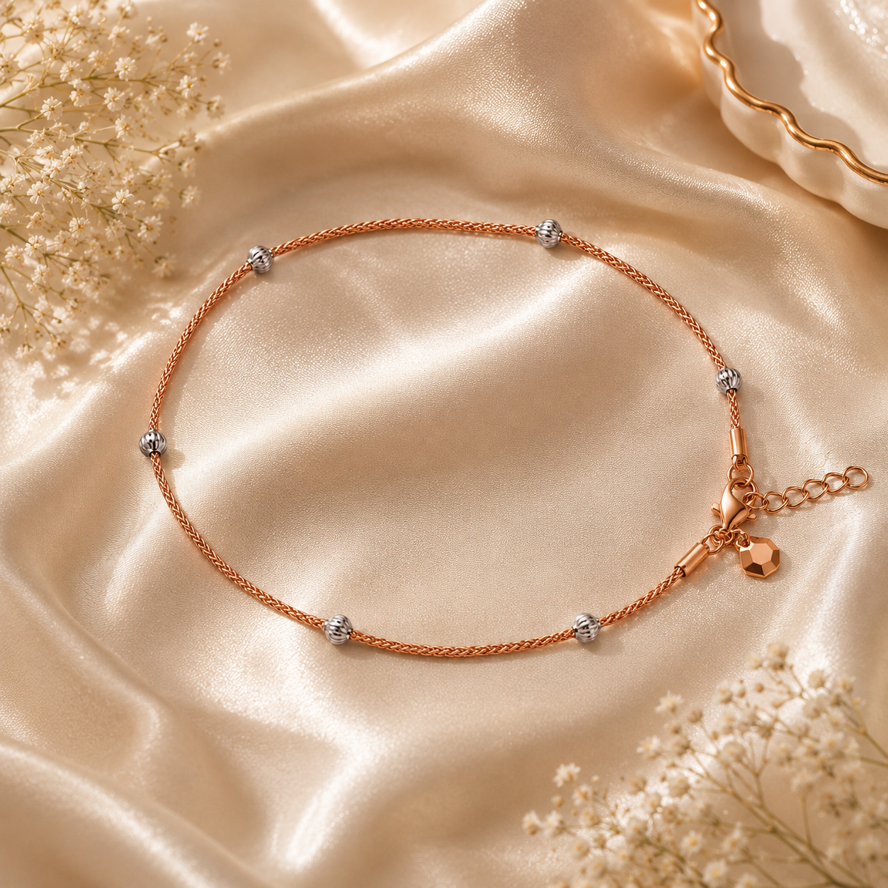 Rose gold anklet with small charms on a beige satin background