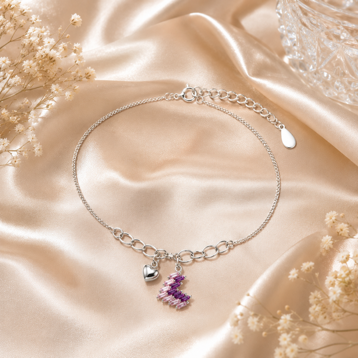 Silver anklet with charms on a beige satin background