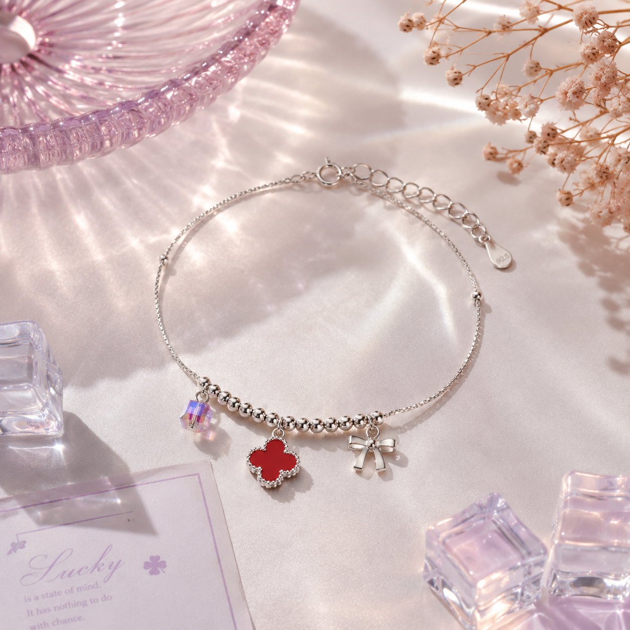 Silver anklet with red flower charm on a soft pink background