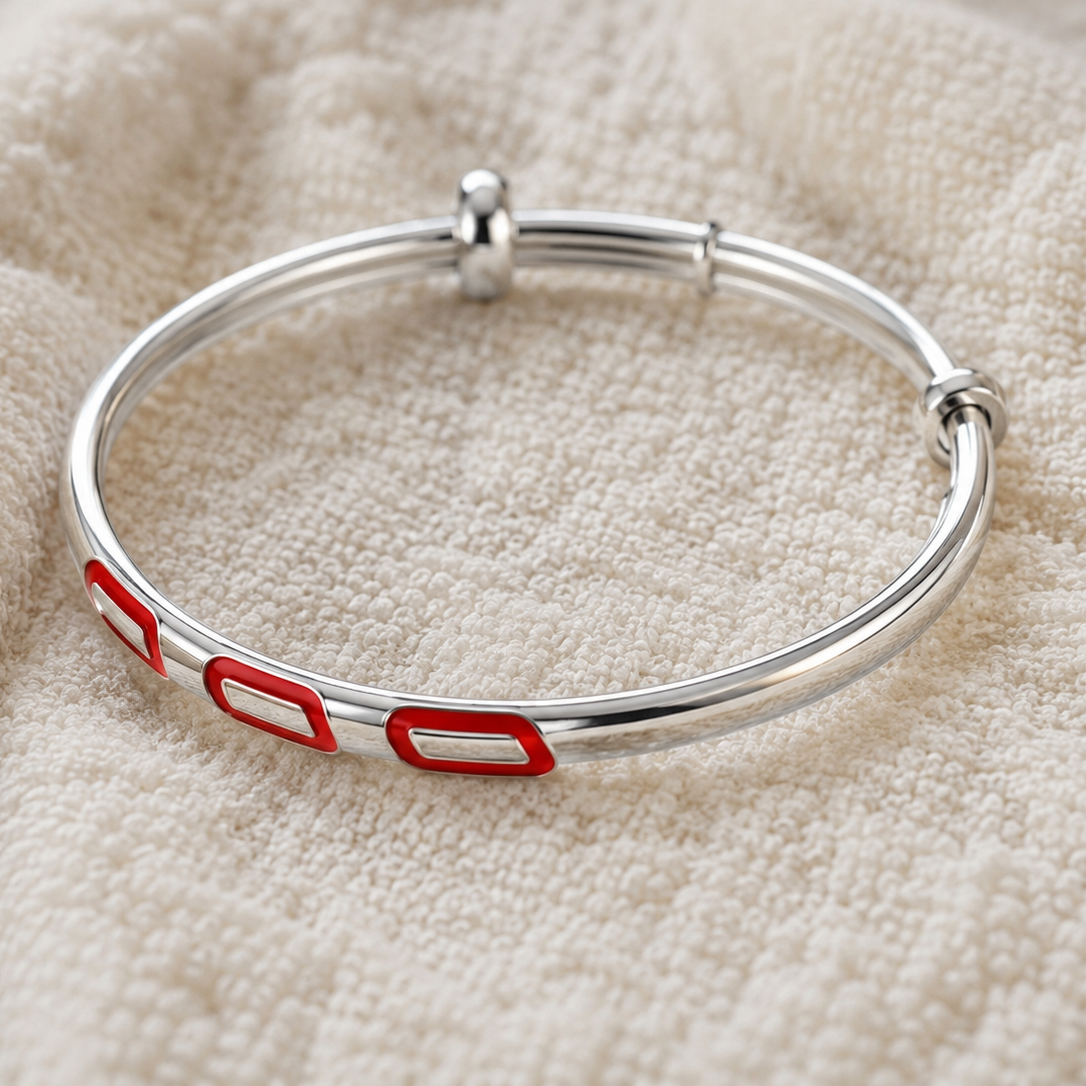 Silver bracelet with red accents on a textured beige surface