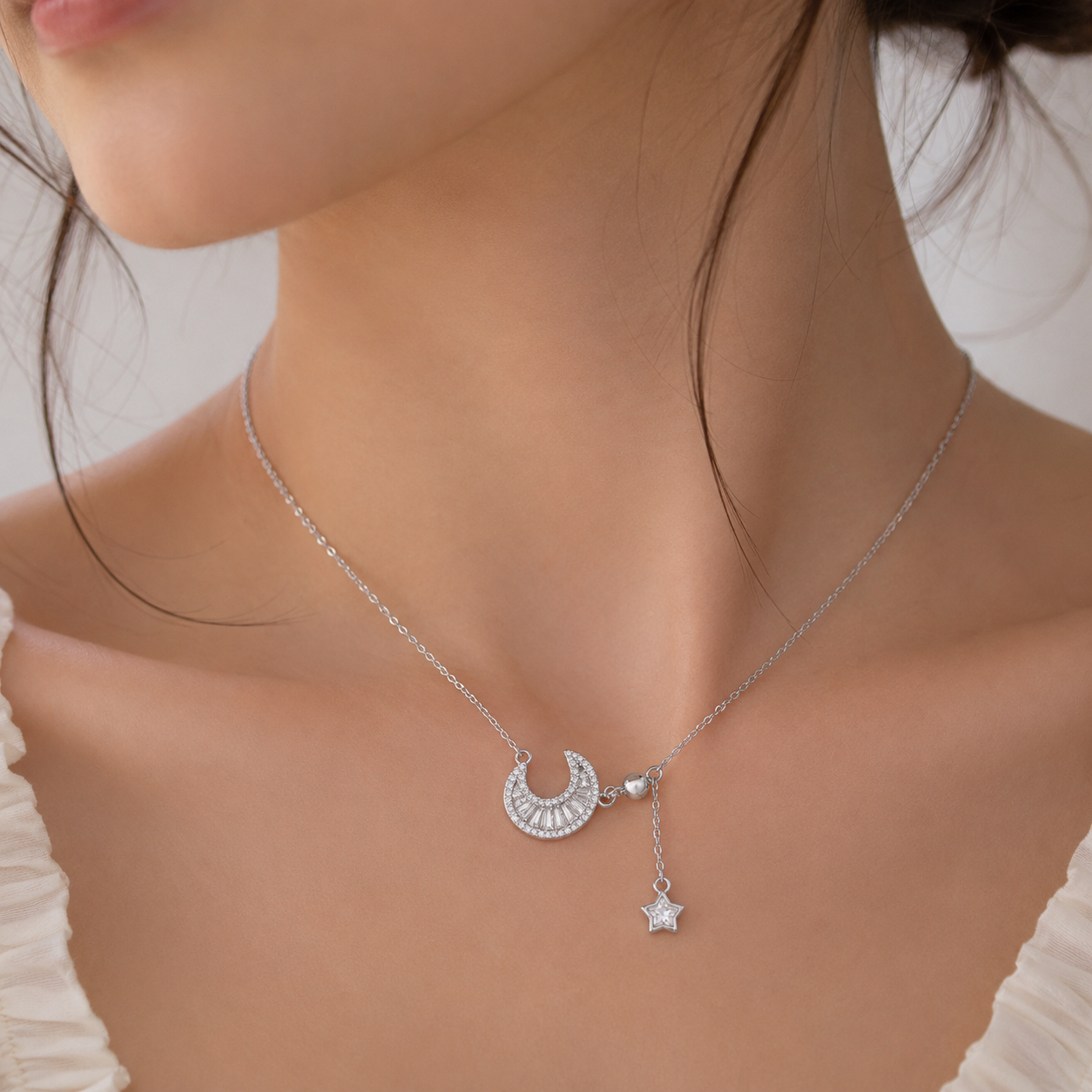 Silver necklace with a crescent moon and star pendant on a model.