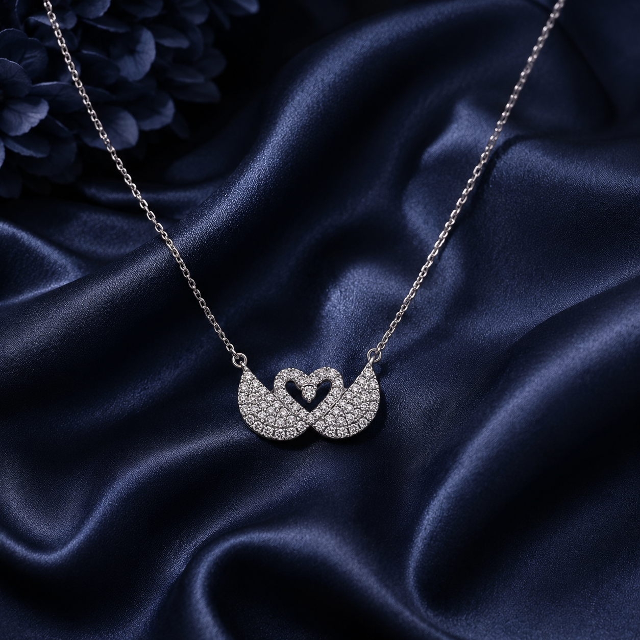 Silver necklace with a heart-shaped pendant on a dark blue satin background