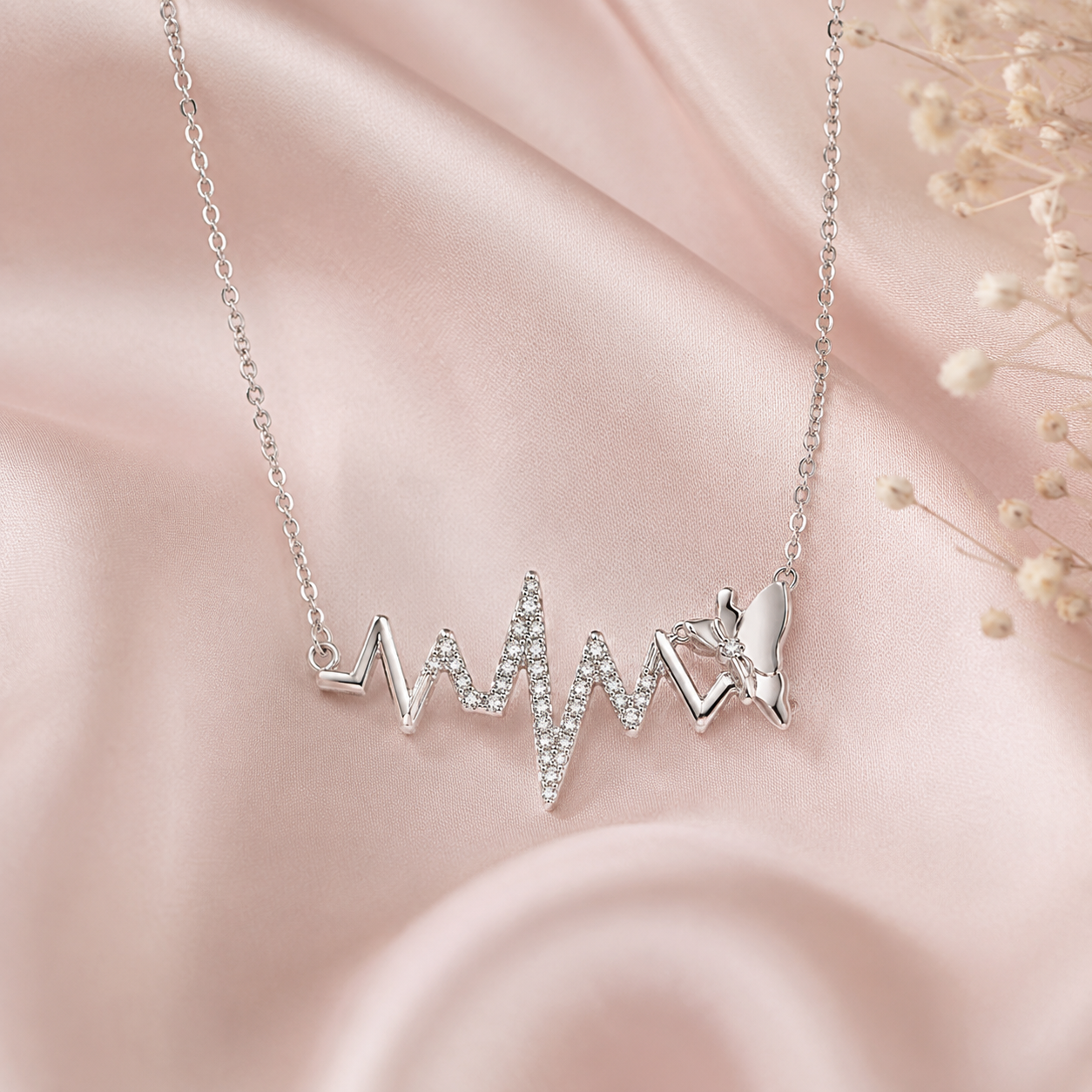 Silver necklace with heart and butterfly pendant on a pink fabric background