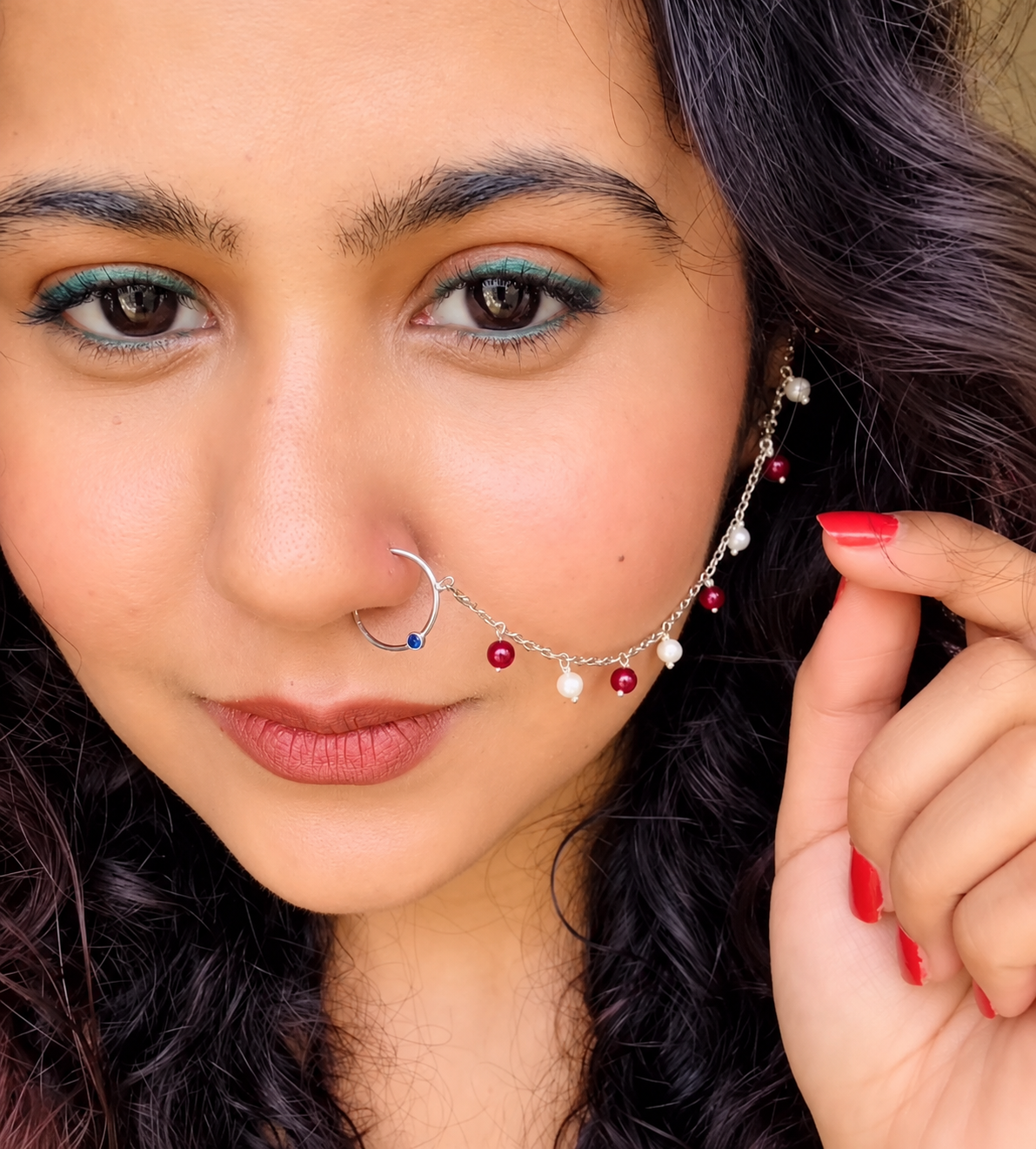 Nose Chain Jewellery in fine sterling silver worn as a lifestyle look, featuring an ultra-thin delicate link draped accent line dotted with alternate crimson and white pearl beads by Rivansh.