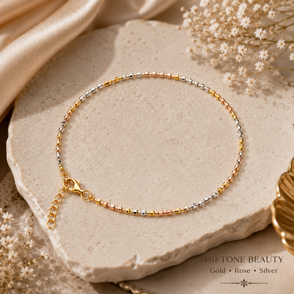 Three-tone gold anklet on a stone surface with dried flowers, Fretone Beauty branding visible.